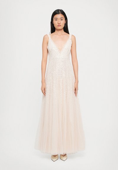 Robe en tulle perlé beige clair avec un décolleté en V profond, de fines bretelles et une jupe fluide. Présente des ornements dispersés sur toute la surface.