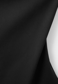 Zwart glad stof gedrapeerd over een wit oppervlak, met textuur en een plooi aan de rechterkant.