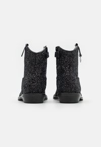 Černé kotníkové boty pokryté třpytkami, s kulatou špičkou, nízkým klínovým podpatkem a dvěma poutky na zadní straně pro snadné oblékaní.