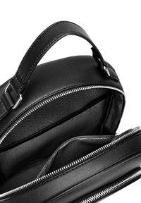 Schwarze Ledertasche mit Reißverschluss, Griff und Innenfächern mit einem Zickzackmuster im Inneren. Glatte Oberfläche und elegantes Design.