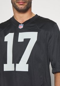 Mand iført en sort NFL-trøje med_NUMBER_ 17 i stort hvidt tryk på forsiden, vist fra brystet og op.