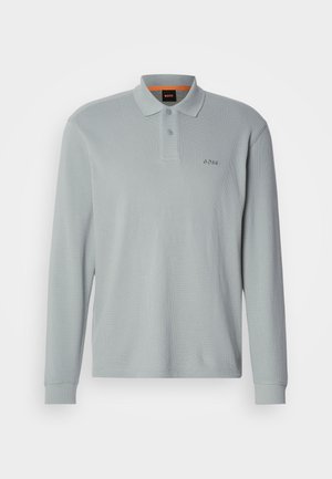 Camisa polo de manga larga en gris claro con una tela texturizada. Presenta un cuello, un cierre de dos botones y un logo bordado en el pecho.