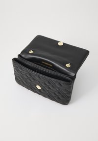 Borsa a tracolla in pelle trapuntata nera con hardware dorato, chiusura a pattina e tasca interna con zip. Marchio visibile all'interno.