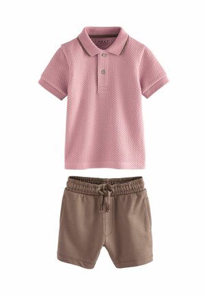 Polo texturé rose à manches courtes avec des shorts à cordon de serrage marron. Le polo a deux boutons et un col contrasté ; les shorts présentent des poches latérales.