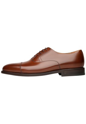 Chaussure oxford en cuir marron avec une finition lisse, système de laçage fermé, bout arrondi et talon bas empilé. Détails de couture subtils présents.