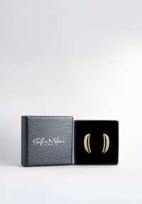 Guldörhängen i form av hoops med flätad textur, presenterade i en svart sammetfodrad låda med silverbranding på ett texturerat grått omslag.