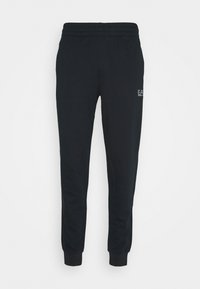 Pantalons de jogging noirs en tissu doux, avec une taille élastique et des poignets, portant un petit logo sur la cuisse supérieure gauche.