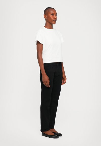 White cropped t-shirt with short sleeves, paired with black slim-fit jeans and black flats, displayed against a light background.