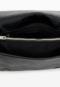 Black textured leather clutch bag with a zip closure. Interior features a smooth black lining and a zip pocket for organization.