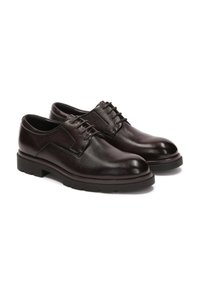 Zapatos de cuero marrón oscuro con una textura suave, puntera redondeada y un icónico diseño de cordones. La suela presenta un ligero relieve para mayor agarre.
