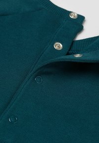 Türkis gestricktes Kleidungsstück mit einem gerippten Kragen, ausgestattet mit metallischen und plastikbeschichteten Druckknöpfen entlang der Knopfleiste zur Schließung.