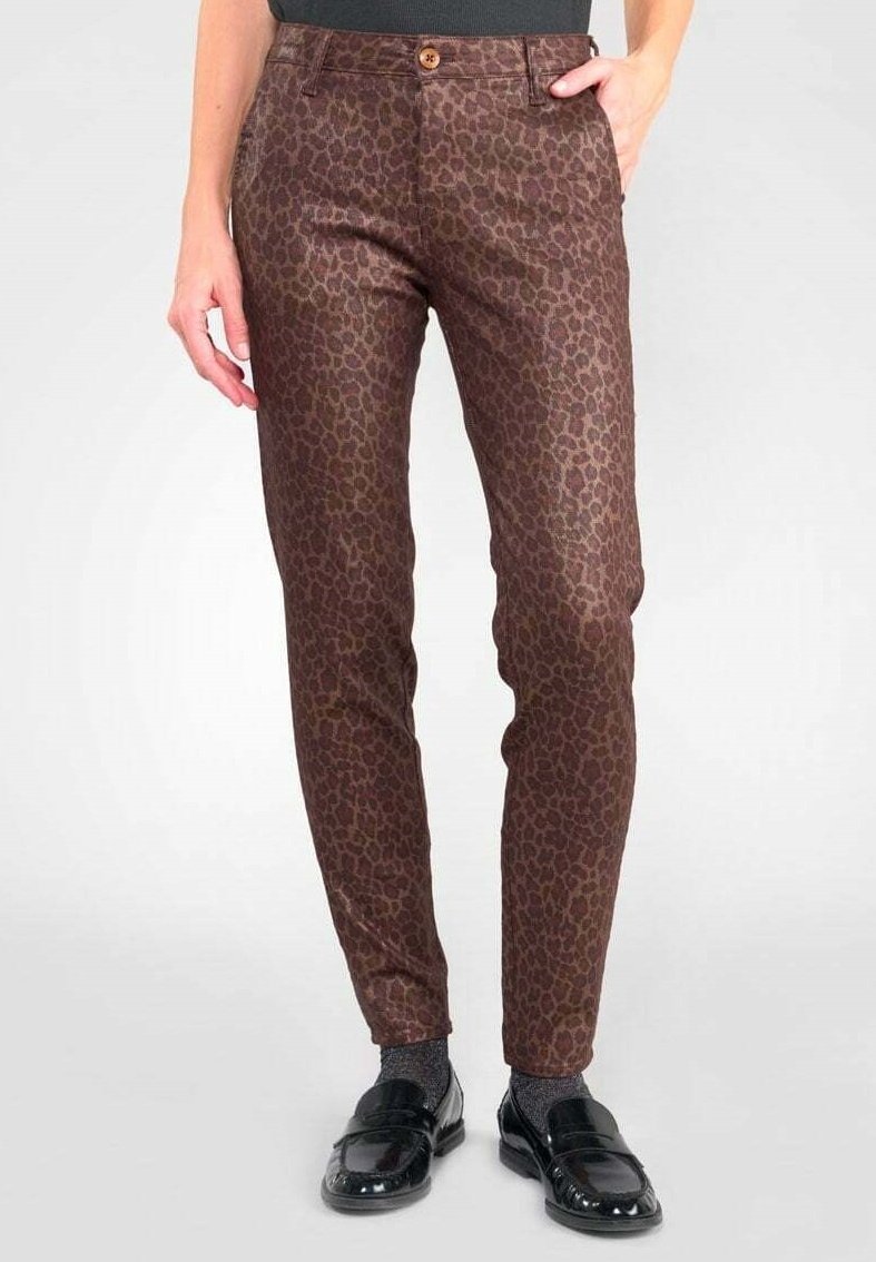 Pantalon marron cintré avec un imprimé léopard discret, fermeture par boutons marron, porté avec des mocassins noirs et des chaussettes grises.