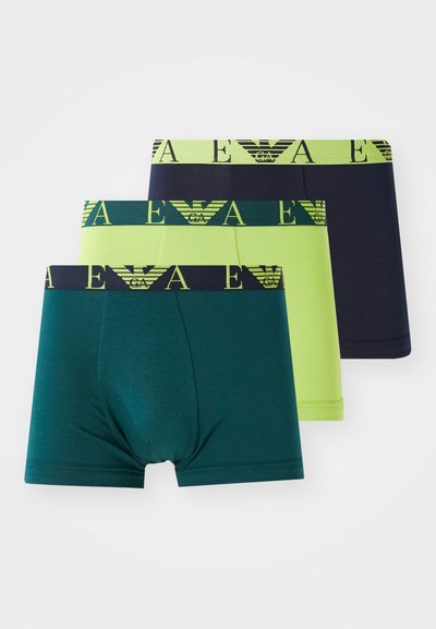 Tre par med boxershorts i grønn, limegrønn og marineblå, hver med kontrastfargede elastiske midjebånd med logo i gult.
