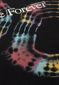 Zwarte stof met een tie-dye patroon in pasteltinten, waaronder roze, blauw en geel. "Tomorrowland Forever" is in wit gedrukt.