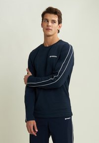 Maglietta a maniche lunghe blu navy con profili bianchi lungo le maniche e un piccolo logo "Freddy" sul petto. Realizzata in un tessuto morbido e liscio.