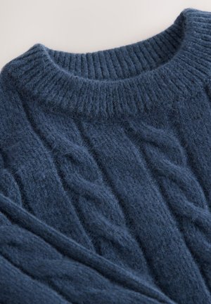 Jersey de punto grueso azul marino con cuello redondo acanalado y textura borrosa, que presenta un patrón de hebras retorcidas en toda la tela.