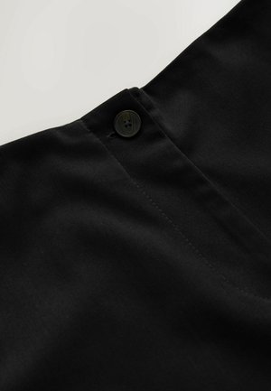 Svart tyg med en mjuk textur, med en knappstängning och en prydlig söm längs kanten, vilket indikerar skräddarsydd design och konstruktion.