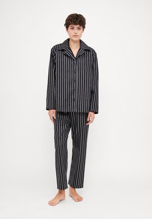 Stribet sort/hvid pyjamas sæt med knaplukning, krave og matchende lige ben bukser, lavet af blødt stof.