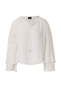 Blouse blanche à manches longues avec des manches en cloche superposées et un décolleté en V noué, ornée de petites perles métalliques sur les cordons.