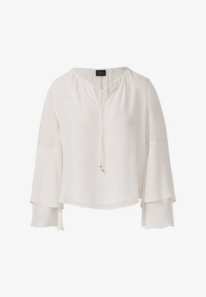 Blouse blanche à manches longues avec des manches en cloche superposées et un décolleté en V noué, ornée de petites perles métalliques sur les cordons.