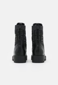 Mustat nilkkurit, joissa on tekstuuri päällinen, jossa on logo-kuvio ja sileät nahka-yksityiskohdat. Kestävä kumipohja, jossa on kohtalainen korkeus.