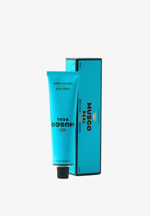 MUSGO REAL Rasiercreme-Tube in leuchtendem Blau mit schwarzem Text. Enthält einen schwarzen Klappverschluss. Wird begleitet von einer passenden Verpackungsschachtel in leuchtendem Blau.