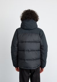 Sort puffersjakke med hætte, har quiltede sektioner, lavet af blankt, glat materiale, designet til varme og komfort.