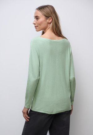 Mintgroene langemouwtruien met een losse pasvorm, brede halslijn en zachte textuur, gedragen met donkergrijze broek.