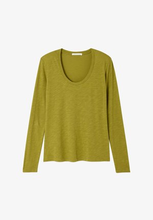 Garām piedurknēm, olīvu zaļā viegla adīta virskrekla topiņš ar noapaļotu izgriezumu, attēlots horizontālā pozīcijā uz balta fona.