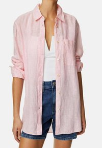 Lichtroze en wit gestreepte overhemd met knopen, gemaakt van stof, met een borstzak, lange mouwen opgerold bij de manchetten, gedragen over een wit tanktop.