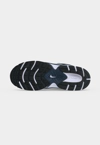 Μαύρη και λευκή σόλα παπουτσιού Nike με υφασμένο πέλμα και ορατό λογότυπο Nike σε απλό ανοιχτό γκρι φόντο.