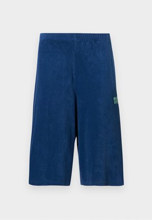 Marineblauwe knielange korte broek met elastische tailleband en een klein groen logo op de rechterdij, weergegeven op een effen achtergrond.