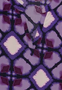 Lila gemusterter Stoff mit abstrakten Formen in Dunkellila, Lavendel und blassrosa. Auffälliger V-Ausschnitt und weiche Textur.