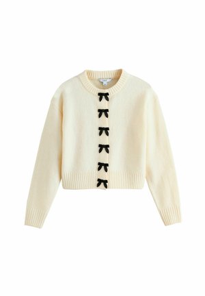 Cremefarbener, kurzer Pullover aus weichem Material mit rundem Ausschnitt, gerippten Bündchen und sechs schwarzen Schleifenakzenten auf der Vorderseite.