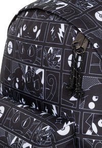Černý batoh s tištěným vzorem různých kreslených postaviček v bílých čtvercích. Obsahuje zipy s černými paracordovými detaily.