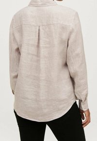 Ljusbeige långärmad skjorta i linne. Har en vik bak, krage och knäppta ärmslut. Texturerad tyg med en mjuk yta.