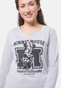 Maglietta a maniche lunghe grigia chiaro con una grafica di Minnie Mouse in nero, accompagnata dal testo "MINNIE MOUSE" e "Fierce & Fashionable".