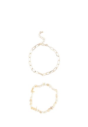 Armband aus goldfarbenem Metall mit verlängerten Gliedern und verstellbarem Verschluss, kombiniert mit einem Armband aus cremefarbenen Steinen.