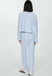 Blauw en wit gestreept tweedelig pyjama-set met een boxy top en losse broek, voorzien van kant langs de zoom. Zachte stof, relaxte pasvorm.