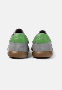 Scarpe grigie in suede con accenti in pelle verde e suole in gomma marrone. Presentano un marchio in rilievo sul tallone e un design arrotondato.