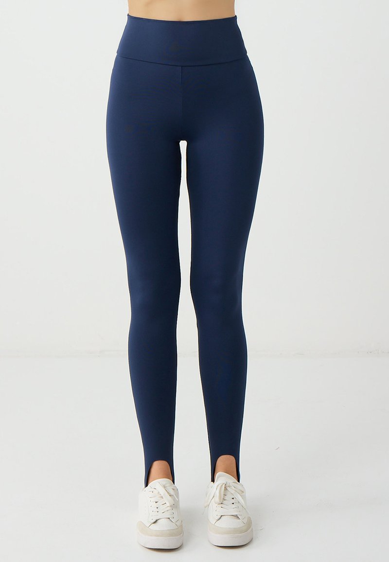 Leggings navy con vita alta, realizzati in un materiale liscio ed elastico. Presentano fessure laterali alla caviglia e un design elegante e aderente.