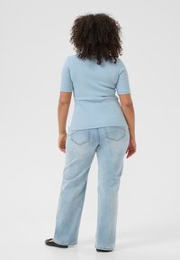 Light blue ribbed short-sleeve top paired with light wash straight-leg jeans. The outfit has a relaxed fit and smooth texture.