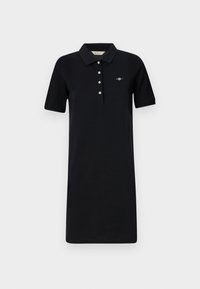 Rochie polo neagră din bumbac, cu guler, mâneci scurte și o închidere cu trei nasturi. Detaliu subtil cu logo brodat.