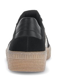 Zwarte suède en leren sneaker met een gestructureerde plateauzool, voorzien van een gladde hielpaneel en horizontale groeven op de zool.