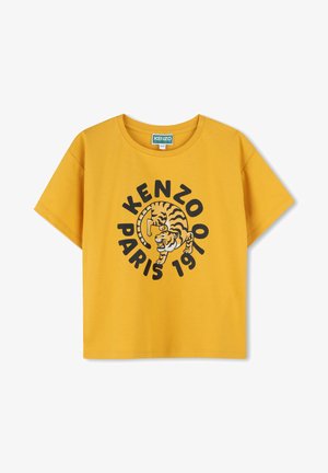 T-shirt en coton jaune avec un graphique noir d'un tigre et le texte "KENZOO PARIS 1970." Manches courtes, col rond et coupe décontractée.