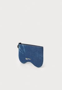 Sininen denimpussi, jossa on sileä pinta, kaareva muoto ja vetoketjulukko. Edessä on logo ja kontrastivärisiä ompelutöitä.