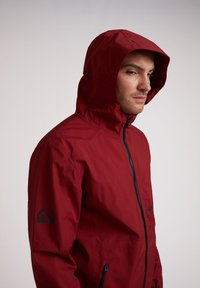 Rode gebreide jack met een rits aan de voorkant, gemaakt van lichtgewicht materiaal. Beschikt over een logo op de mouw en een getextureerde stof.