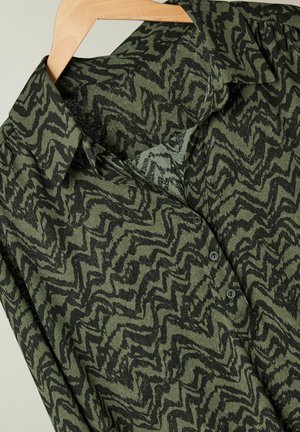 Groene overhemdbloes met een zigzagpatroon in donkergroen en zwart. Gemaakt van gestructureerde stof met een gestructureerde kraag en knopen.