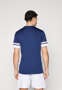 Navy athletic shirt made of smooth fabric, featuring white and navy striped accent sleeves. Short sleeves and crew neckline.