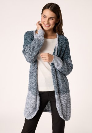Open-front cardigan in textured knit, featuring a gradient of dark teal to light gray. Long sleeves and a relaxed fit, paired with a light top.